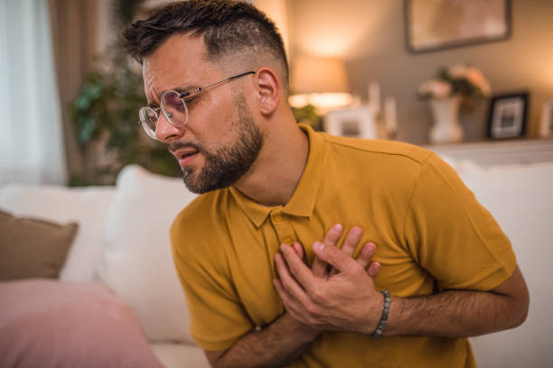 istock Man has severe chest pain while sitting on sofa in living room 2179549445