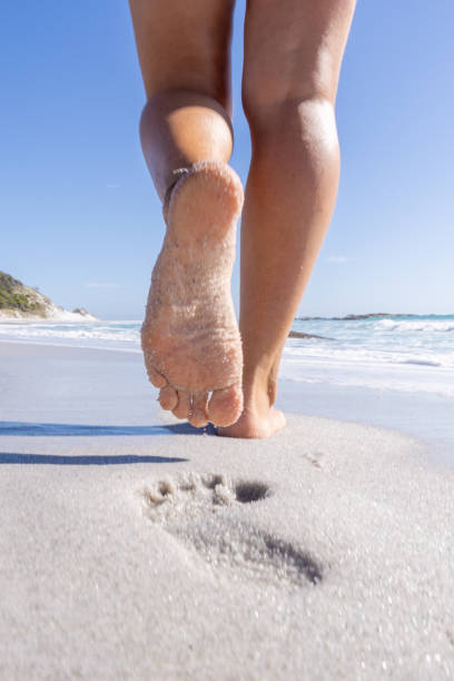 Barefoot Steps: Woman Walking on Sandy Beach