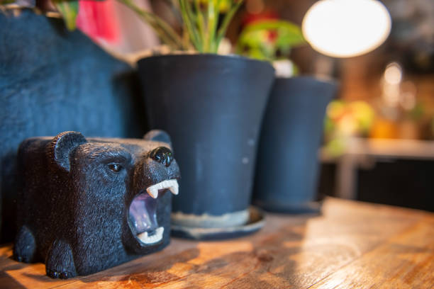 Black bear model decor on wooden table by tree pot inside cafe and restaurant. Cure figure.