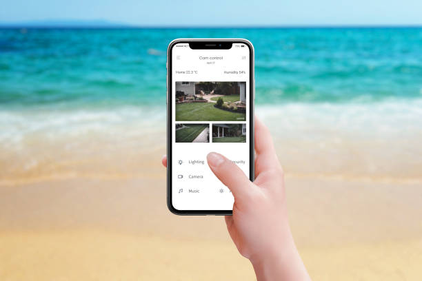 Monitoring home security cameras from the beach using a smartphone app, ensuring peace of mind while enjoying a seaside vacation and keeping an eye on the backyard