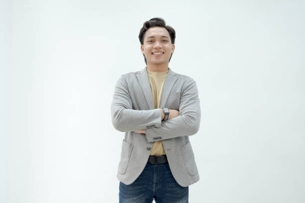 istock Confident young man in a grey blazer standing with arms crossed against a plain background in a casual and approachable manner 2179569366