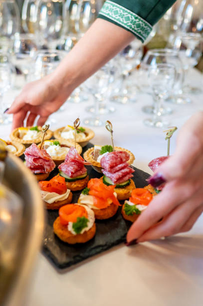 istock A variety of gourmet appetizers elegantly presented on a serving table, with a hand reaching for a dish. Perfect for culinary, catering, or event themes, showcasing the diversity of the food. 2179584131