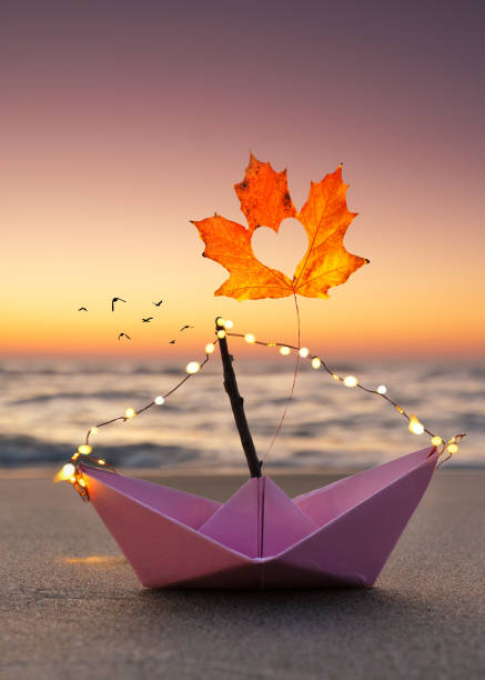 istock paper boat with autumn leaf 2179587378