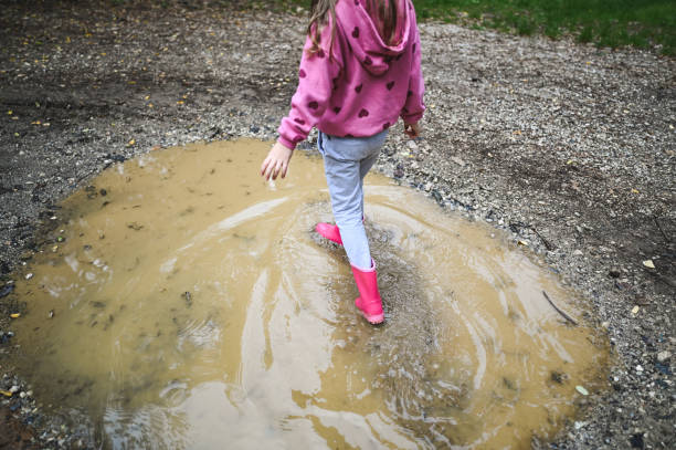 Girl playing in rain puddle