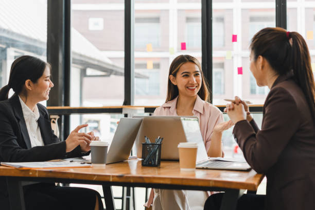 istock Collaborative business meeting with three women discussing ideas at modern office table. They are engaged and smiling, showcasing teamwork and communication 2179591890