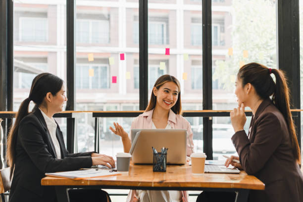 istock Collaborative business meeting with three women discussing ideas at modern office table. They are engaged and smiling, showcasing teamwork and communication 2179592066