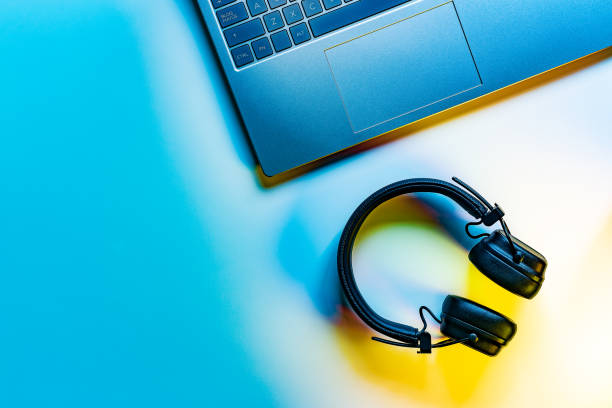 Spain. High angle view of a laptop and wireless over-ear headphones on a white desk.