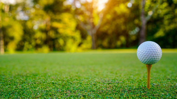istock golf ball on tee in beautiful golf course with sunset. 2179593751
