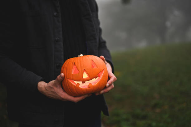 istock holding jack o' lantern in the woods. 2179596457