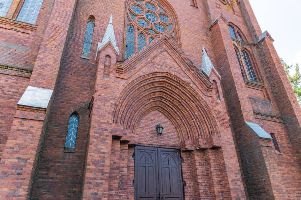 istock Gothic-style church, characterized by its pointed arches, tall spires, and intricate brickwork. The architecture includes large stained glass windows, likely with elaborate designs. 2179603438