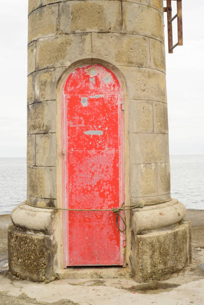 Red metallic door in a small light tower in a port