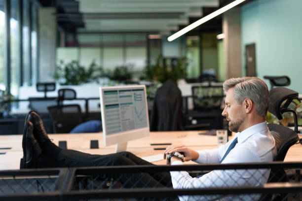istock Handsome businessman sitting in office while looking at watch. 2179621072