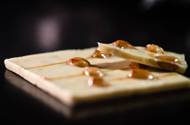 White chocolate with pistachio, fresh orange syrup and almonds. Homemade white chocolate bars on dark wooden table- stock photo