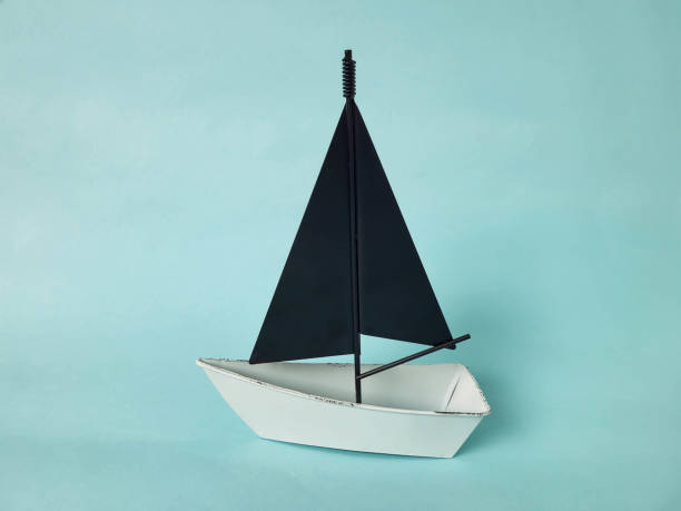 istock A white toy boat with black sails stands on a blue background. 2179629092