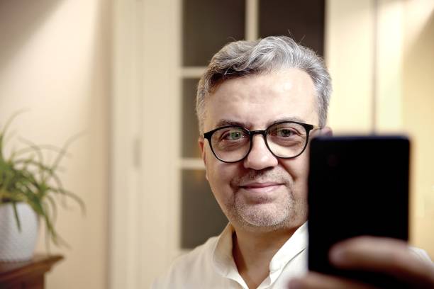 istock A middle-aged businessman smiles while making a video call on his phone 2179635335