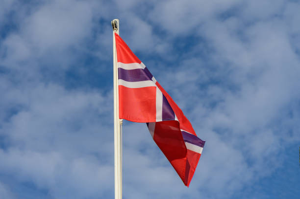 istock Colorful Norwegian flag waving under a bright blue sky with fluffy clouds during a sunny day in Norway 2179638922