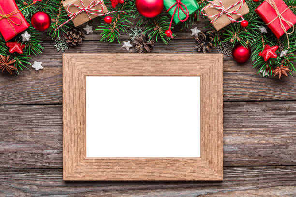 istock Blank photo frame with Christmas decorations, fir tree branches, gift boxes and pine cones on rustic wooden table. Flat lay. Mock up. Happy New Year and winter holidays layout. Top view 2179642839
