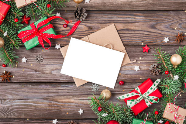 istock Christmas greeting card and envelope with fir branches, gift boxes, red and golden decorations, pine cones on rustic wooden table. Flat lay. Mock up. Happy New Year and winter holidays invitation 2179642987