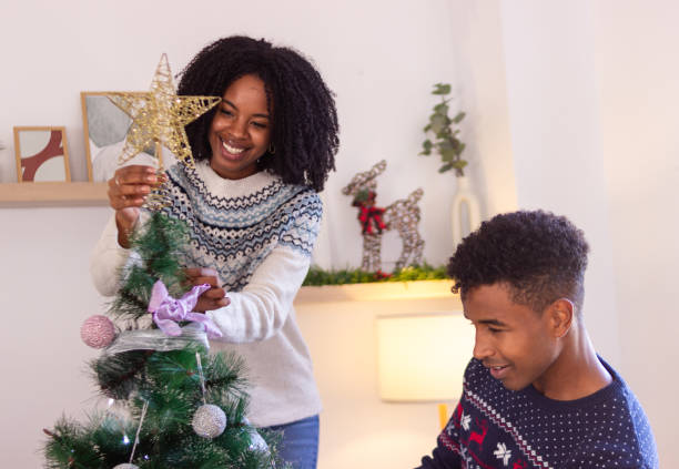 istock Couple decorating christmas tree placing star on top 2179644575