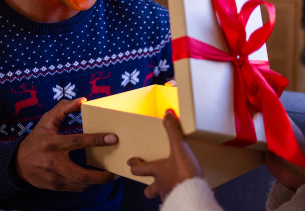 istock Couple opening christmas gift with golden light inside 2179645451