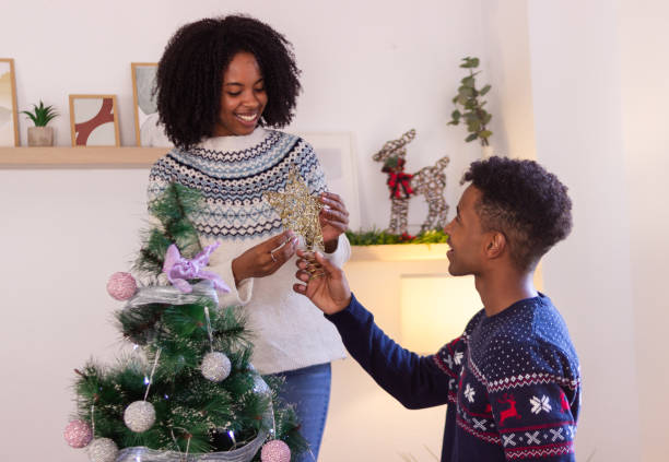istock Young couple decorating christmas tree placing star on top 2179646018