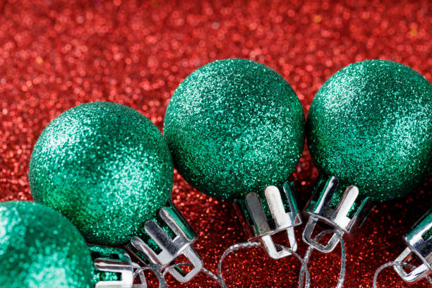 Glossy Green Christmas Decorations on Red Glitter Background for Cheerful Winter Celebration