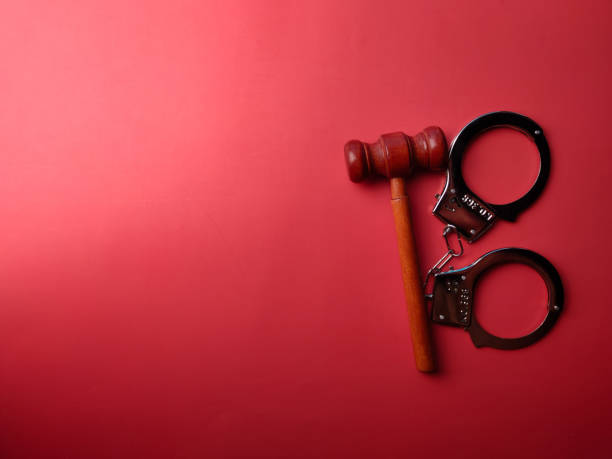 istock Top view gavel and hand cuff with copy and text space on a red background 2179647821
