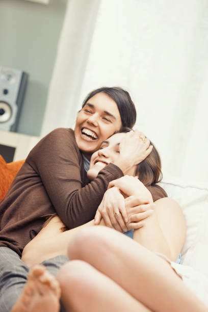 istock Two young women embracing on the sofa and laughing 2179652157