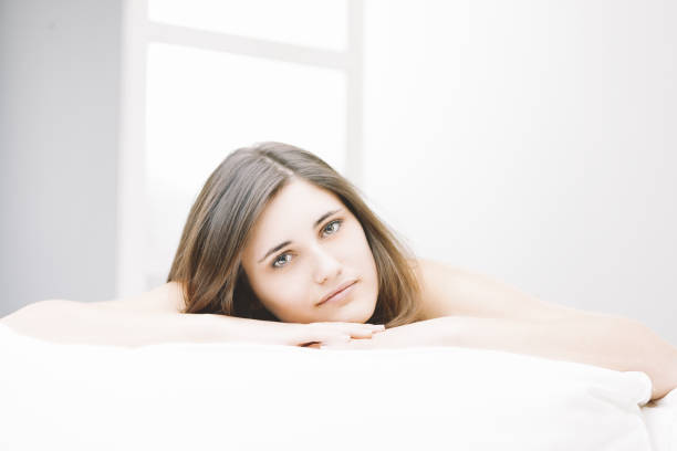 Young woman peacefully relaxes in her cozy, bright bedroom, exuding happiness and tranquility