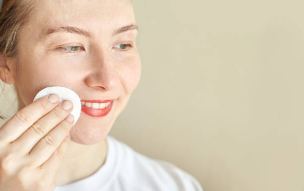 istock Woman smiling while cleansing face with cotton pad for skincare routine 2179654394