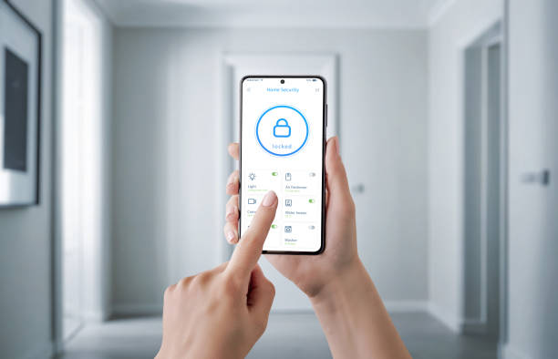 istock Hand holding a smartphone with a security app interface, controlling home safety features like door lock, surveillance camera, and alarms. Concept of modern security, remote monitoring 2179670031