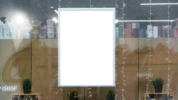 istock Blank illuminated poster frame displayed in storefront window with shelves of products and decorations visible in background 2179670937