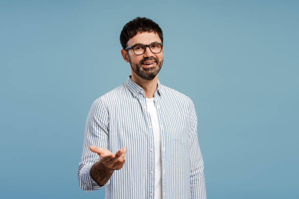 Smiling, attractive bearded man wearing stylish eyeglasses, explaining. Influencer recording video