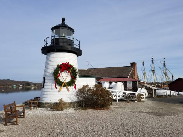 New England Christmas Holiday Lighthouse with wreath at Mystic Connecticut with ship and boats and benches