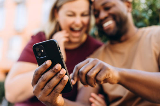 istock Happy multiethnic couple looking at smartphone screen sitting outside 2179680782