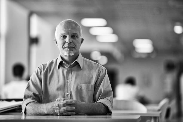 Serious manager sits at his desk, deep in thought, exuding confidence and focus in a black and white office portrait