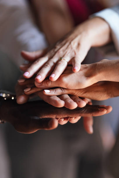 A group of diverse hands joining together in a powerful symbol of teamwork and unity during a business setting. The image conveys cooperation and collaboration with an inclusive and supportive atmosphere.