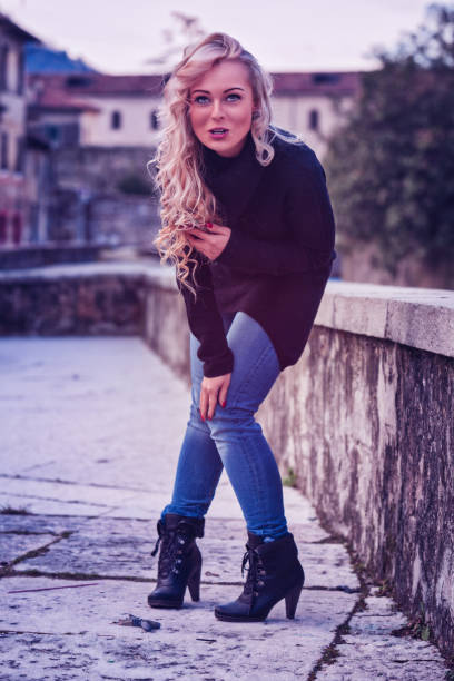 istock Young woman posing leaning on a stone wall in a town 2179687336