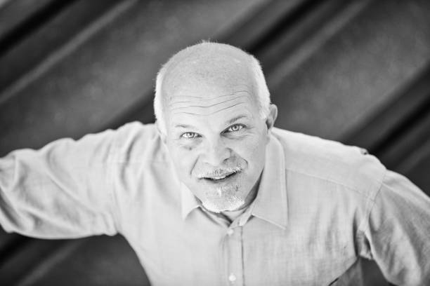 Smiling senior manager poses confidently in a modern office. This black and white portrait captures his successful career