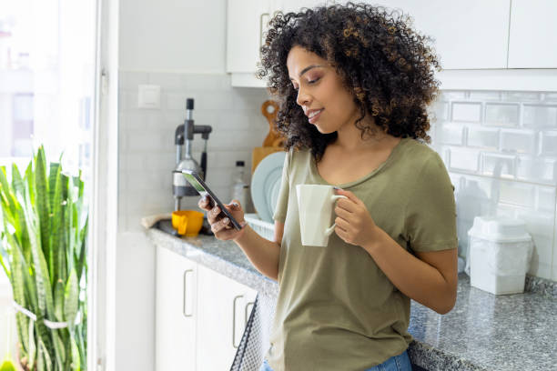 istock Young woman looking at her phone in kitchen 2179697017