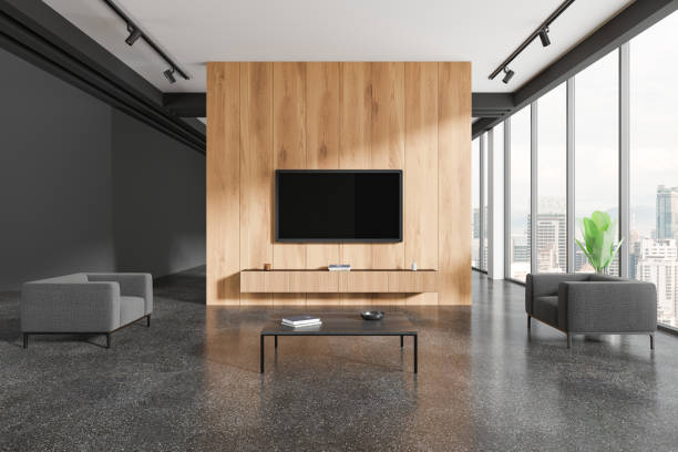 istock Living room with a TV mounted on a wooden wall, two grey sofas, and a coffee table. Large windows with city views. Modern interior design. 3D Rendering 2179701073