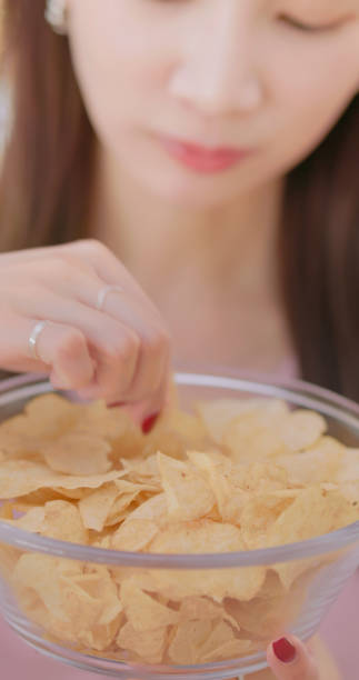 istock woman eat potato chips home 2179701260