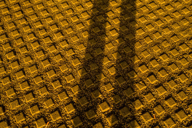 Golden hour sunlight illuminates the ground in Gothenburg, casting long shadows from a nearby bridge. The textured pavement adds depth to the visual display.