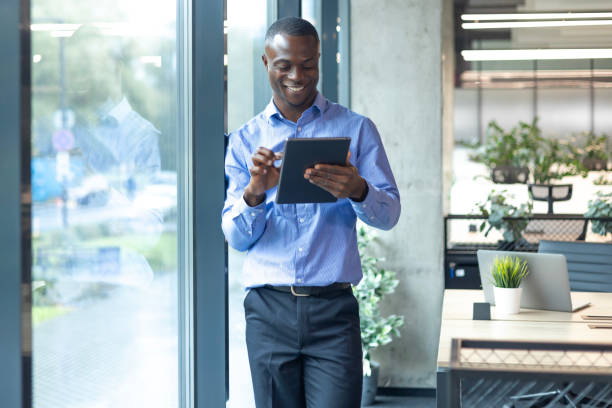 istock Smiling busy african businessman manager using tablet computer standing in office 2179707163