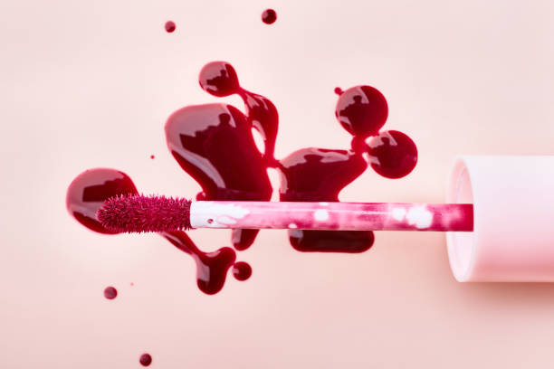 istock Vibrant lip gloss spill on soft pink surface with applicator 2179714464
