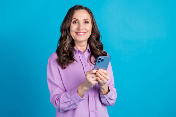Photo of cheerful pretty lady dressed puple blouse texting apple iphone samsung gadget empty space isolated blue color background