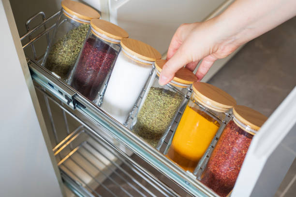 Cropped hand holding jar of spices on kitchen.