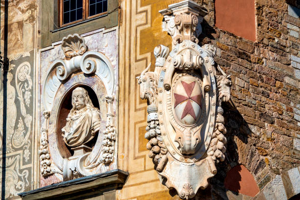 Close-up of the facade of Palazzo della Carovana in Pisa, Italy, featuring a bust and the coat of arms of the Knights of St. Stephen.