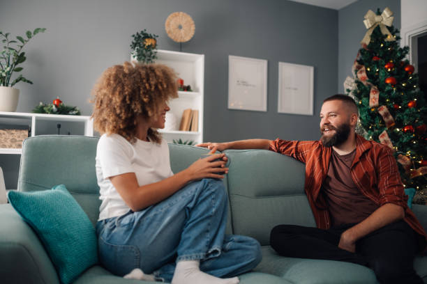 istock Interracial couple relaxing on sofa by christmas tree having a conversation 2179733678