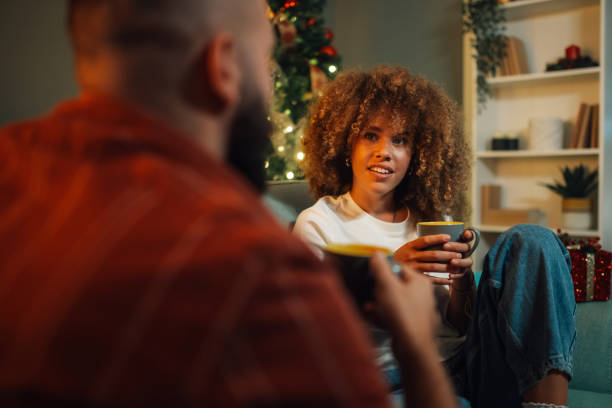 istock Young couple relaxing on sofa drinking coffee by christmas tree 2179733704